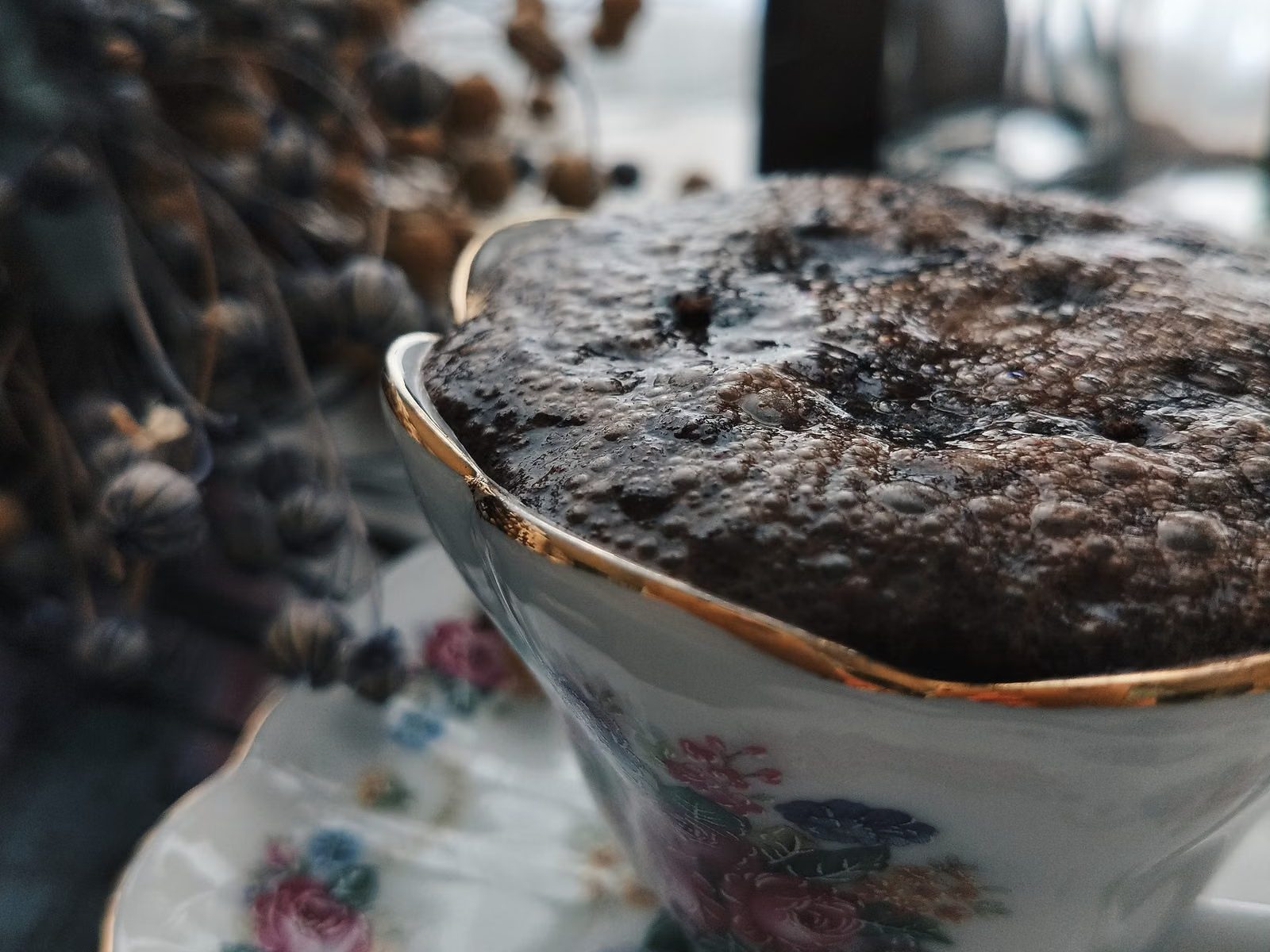 Bizcocho de chocolate esponjoso que sobresale de una taza de porcelana con flores