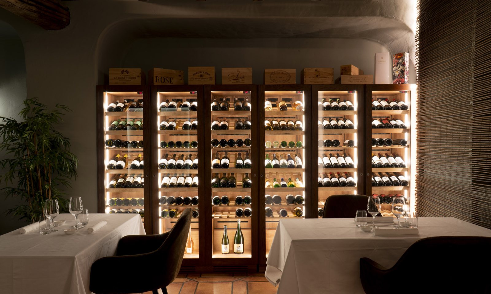 Comedor del restaurante Koku, con mesas montadas y una vitrina de vinos al fondo