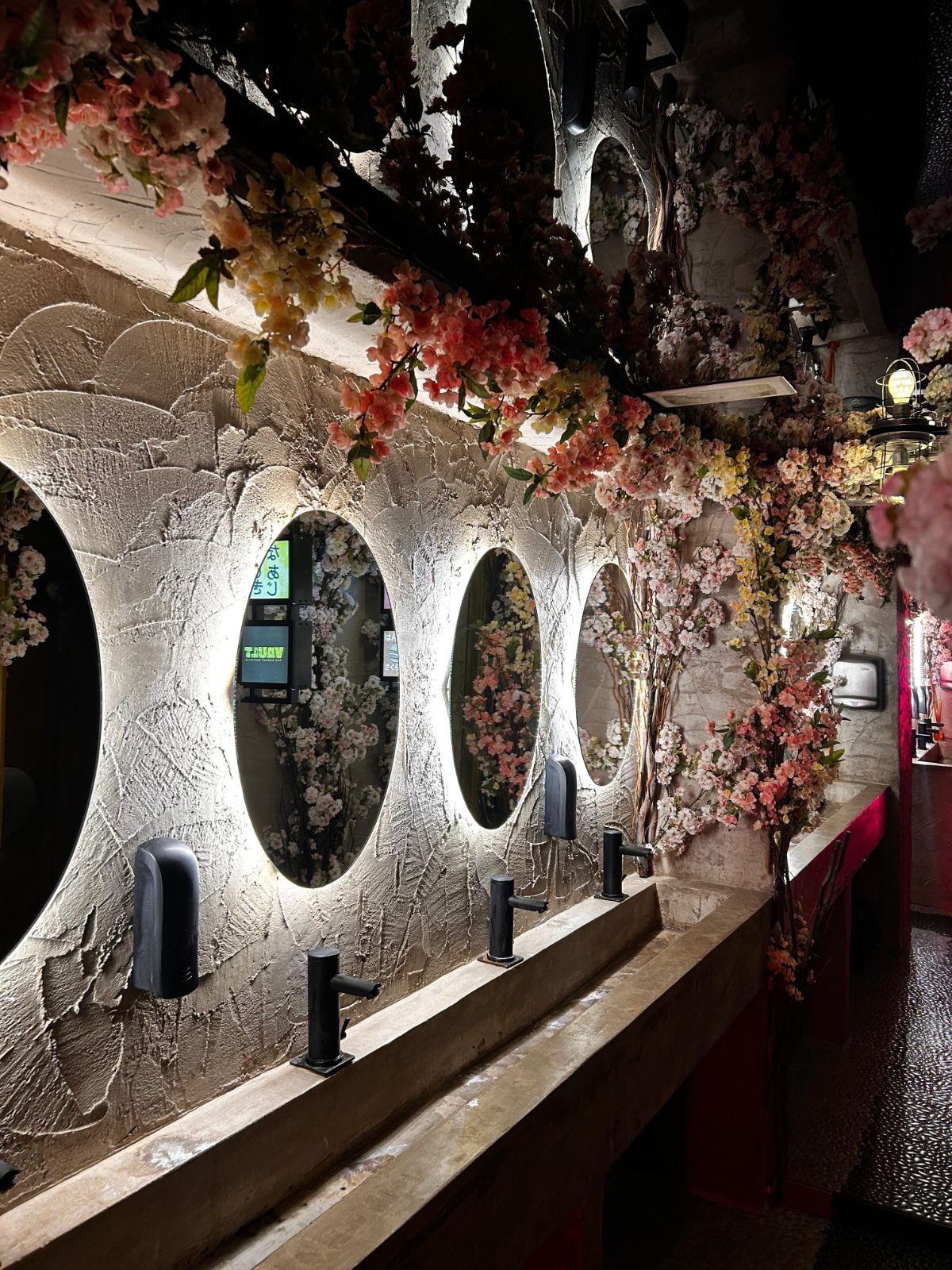 Pasillo de Vault con espejos redondos iluminados y flores colgantes